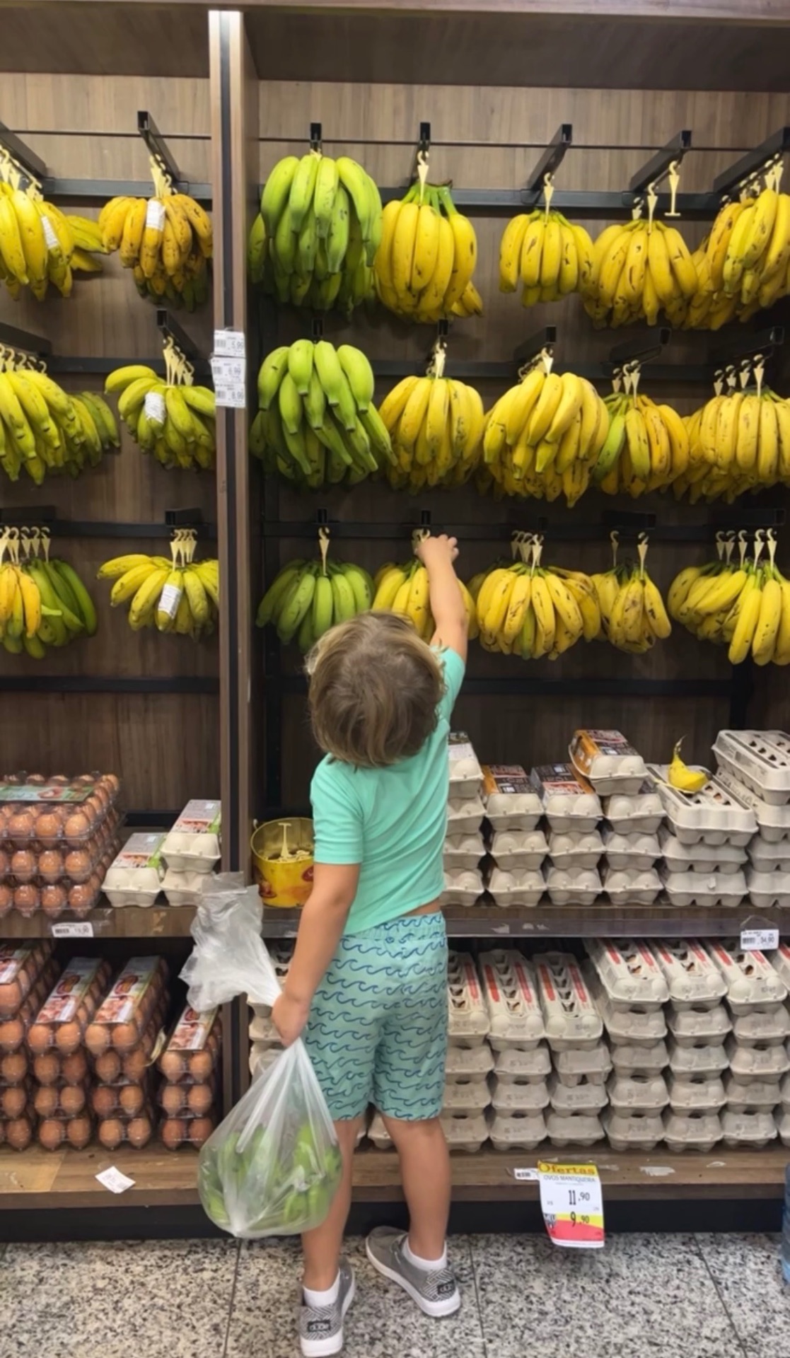 Kid reaching for bananas in a Brazilian market